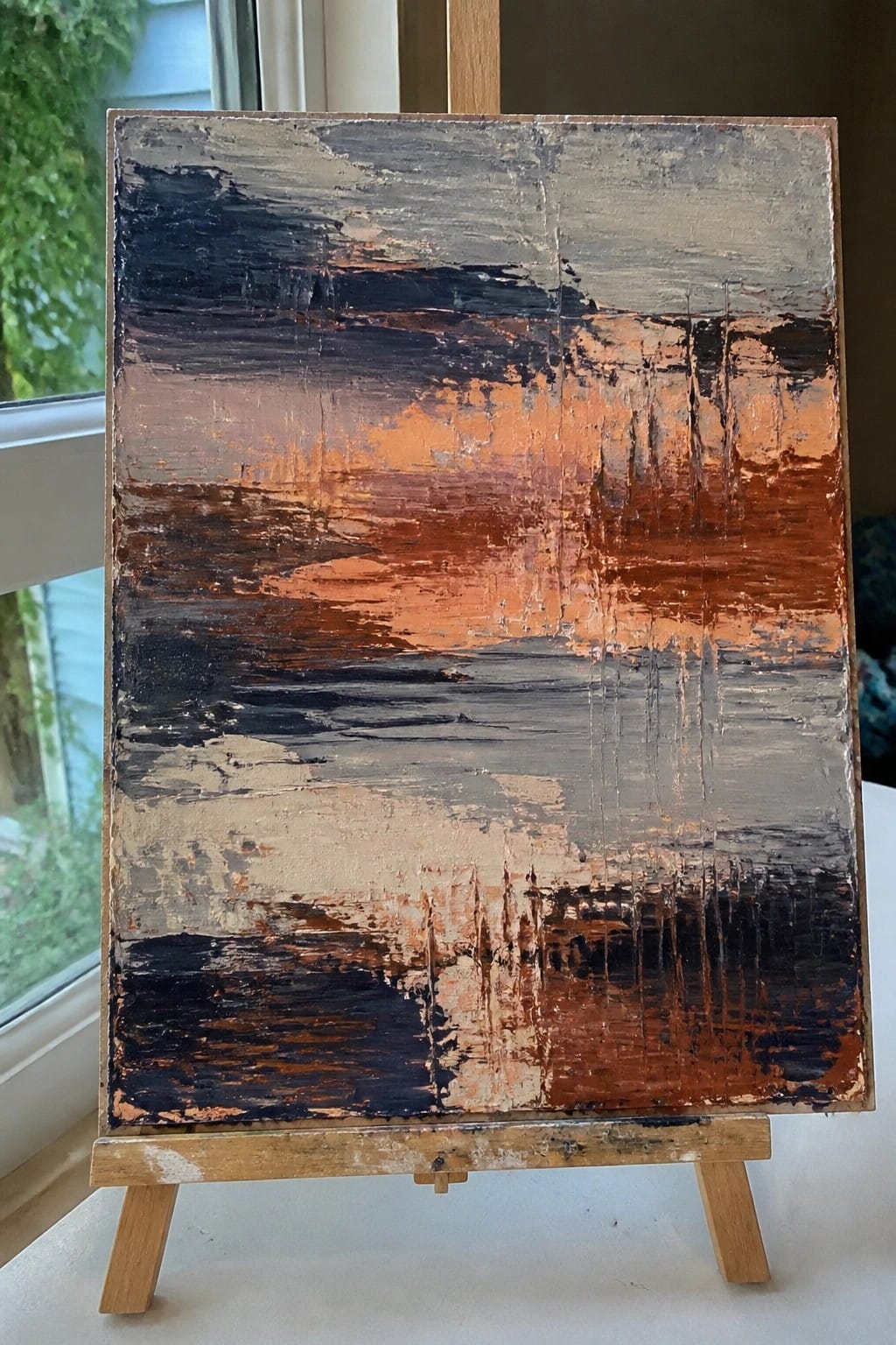 An abstract oil painting on canvas showing horizontal bands of black, orange, gray, and beige with heavy palette knife texture.