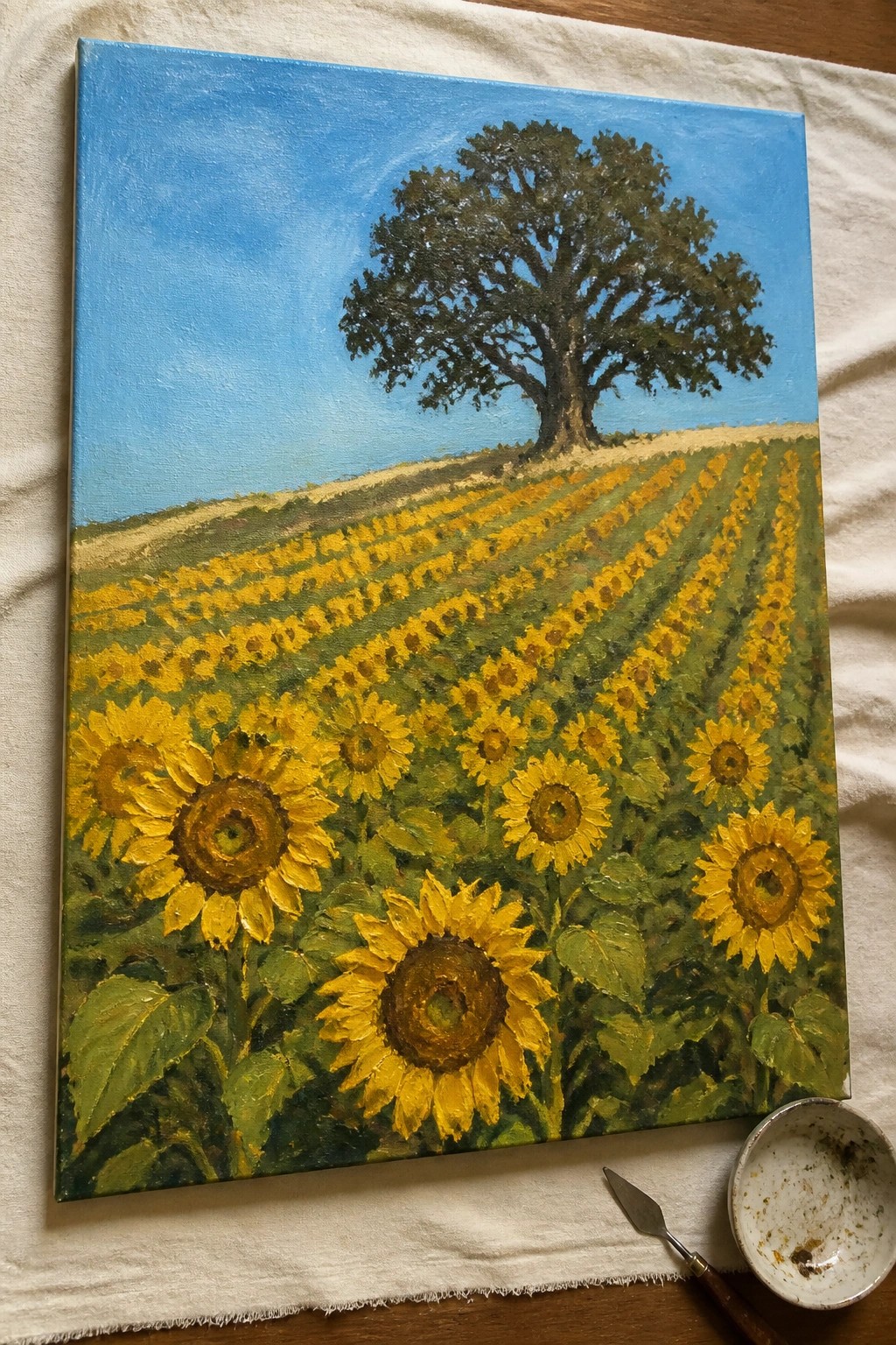 Sunflower field oil painting with tree on hill, palette knife beside canvas