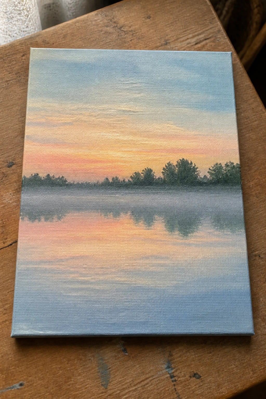Colorful sunset painting on canvas with orange pink sky reflected in calm water with trees