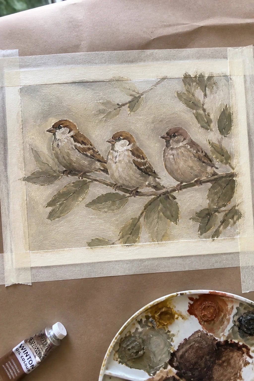 Three sparrows on leafy branch in oil painting with palette and paint tube nearby