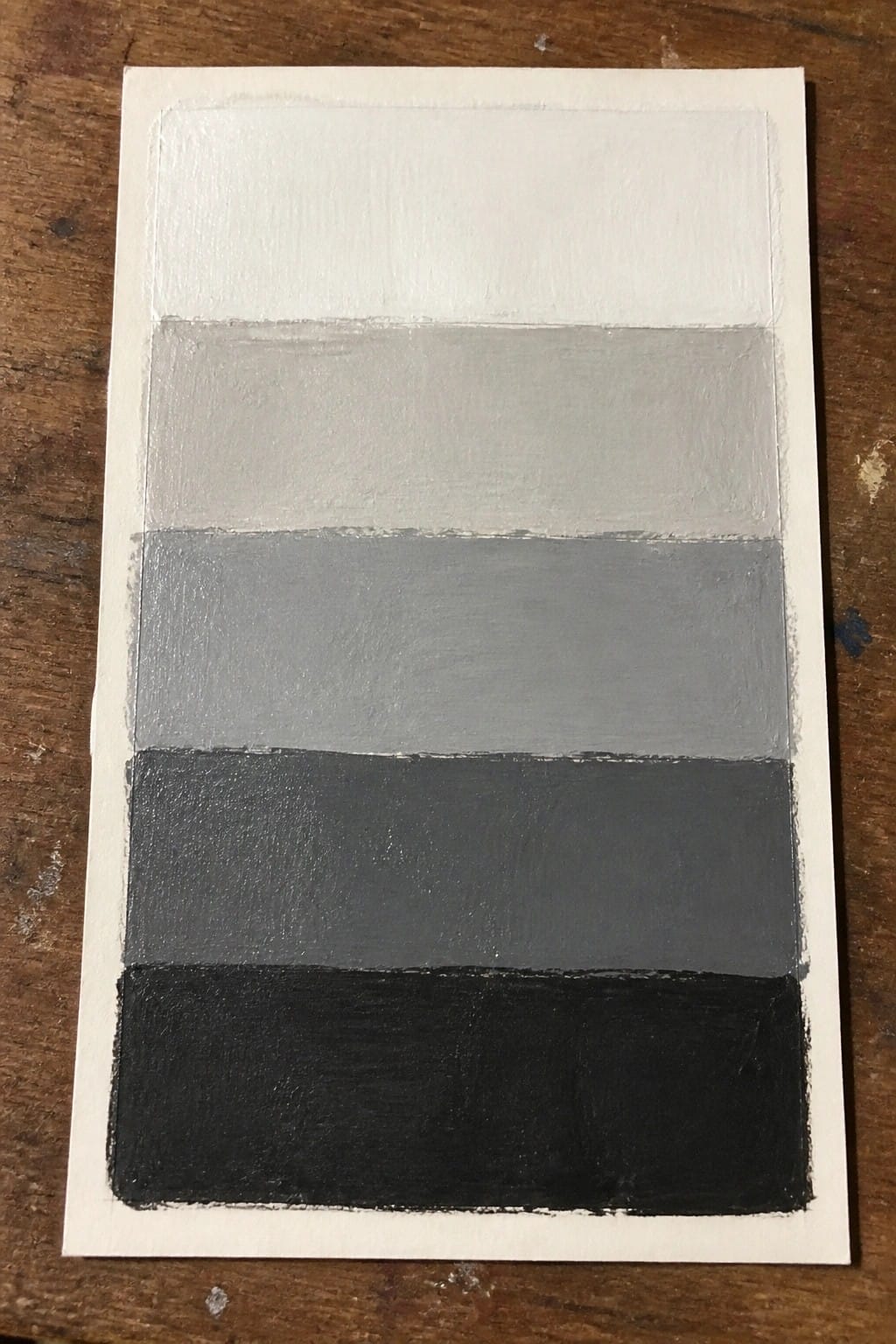 Horizontal gradient painting with five shades of gray from white to black on wood.