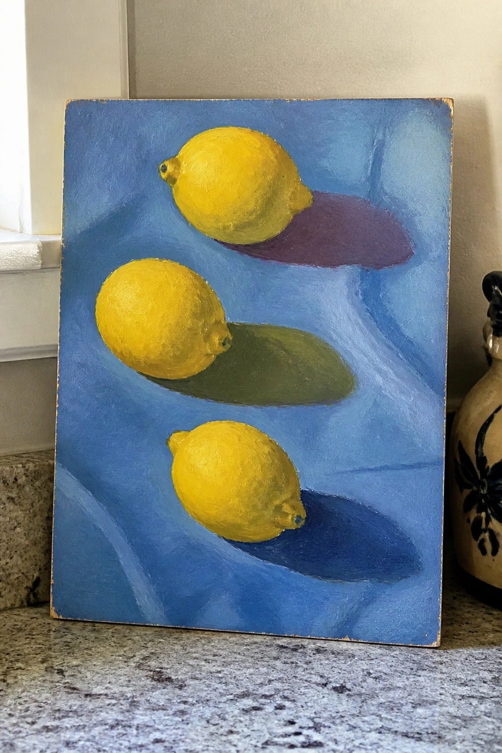 Three yellow lemons with purple, green, and blue shadows on swirling blue canvas