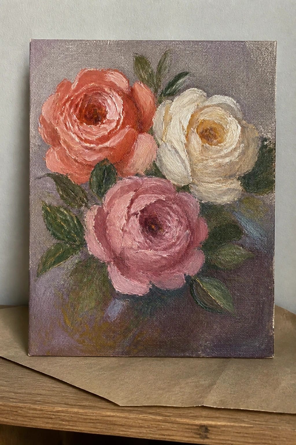 Three roses in coral, pink, and white with green leaves on purple canvas
