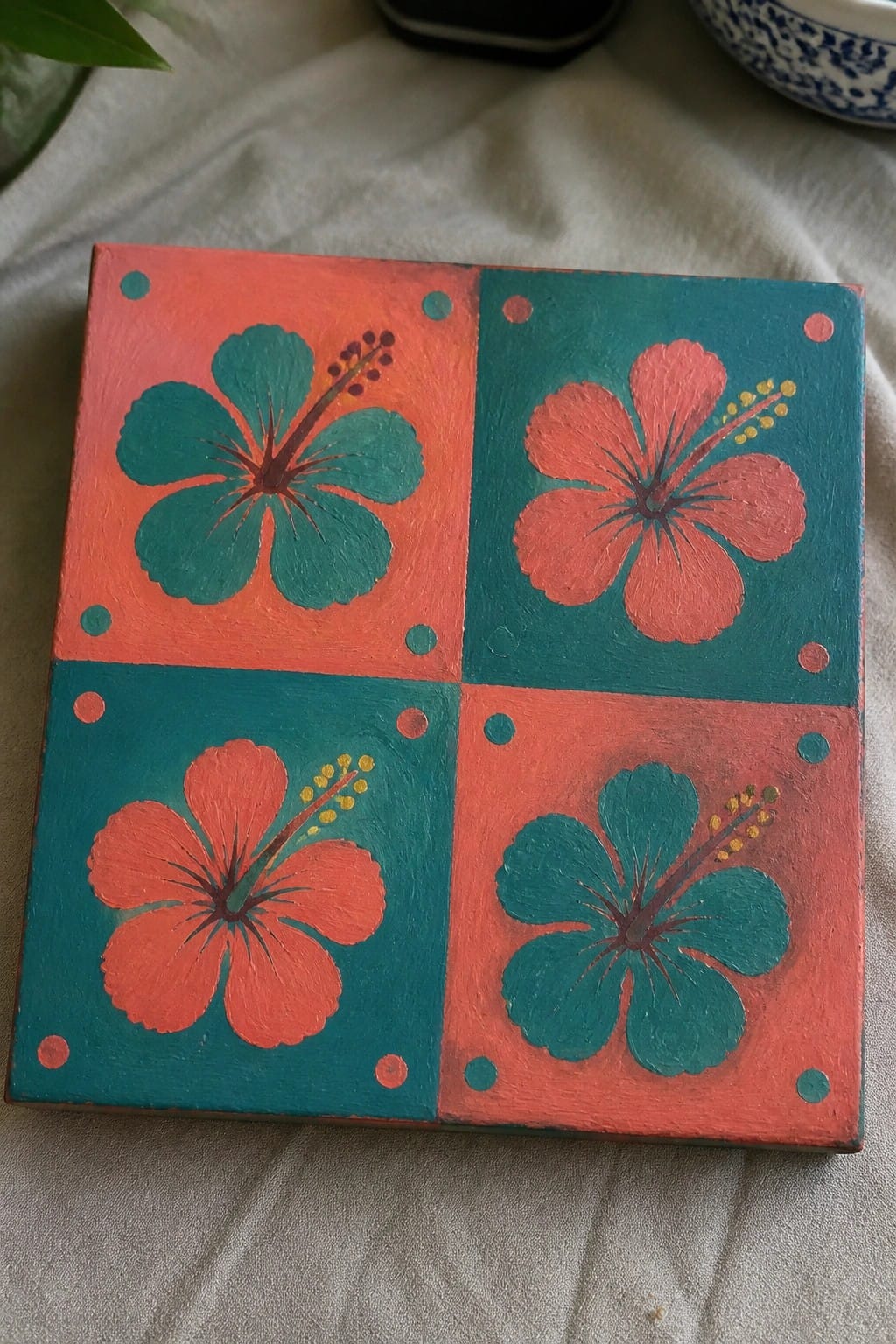 Square canvas with four alternating orange-teal quadrants, each featuring a hibiscus flower and colorful dots.