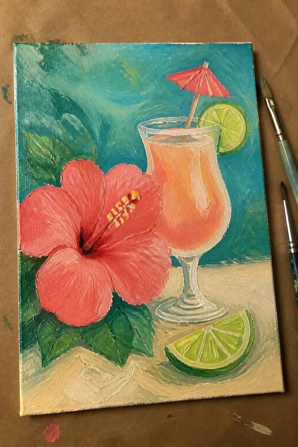 Red hibiscus flower beside orange cocktail with pink umbrella and lime slices