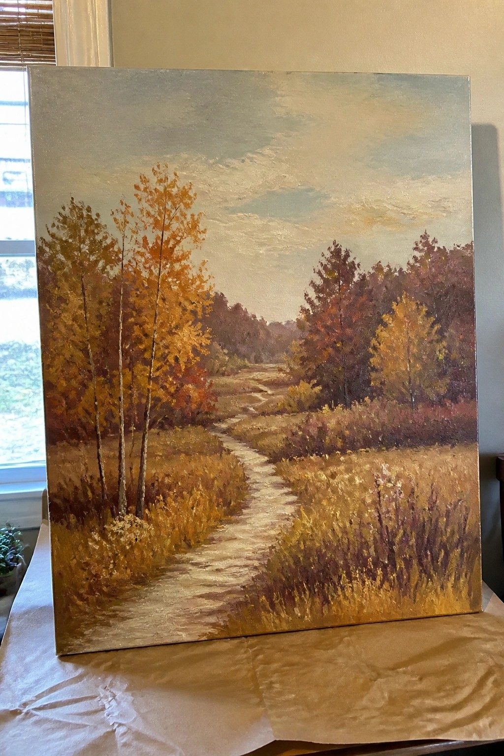 Oil painting of winding path through autumn fields with orange and red trees.