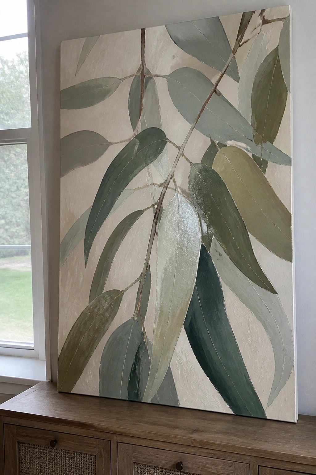 Large eucalyptus leaf painting in muted greens on wooden cabinet