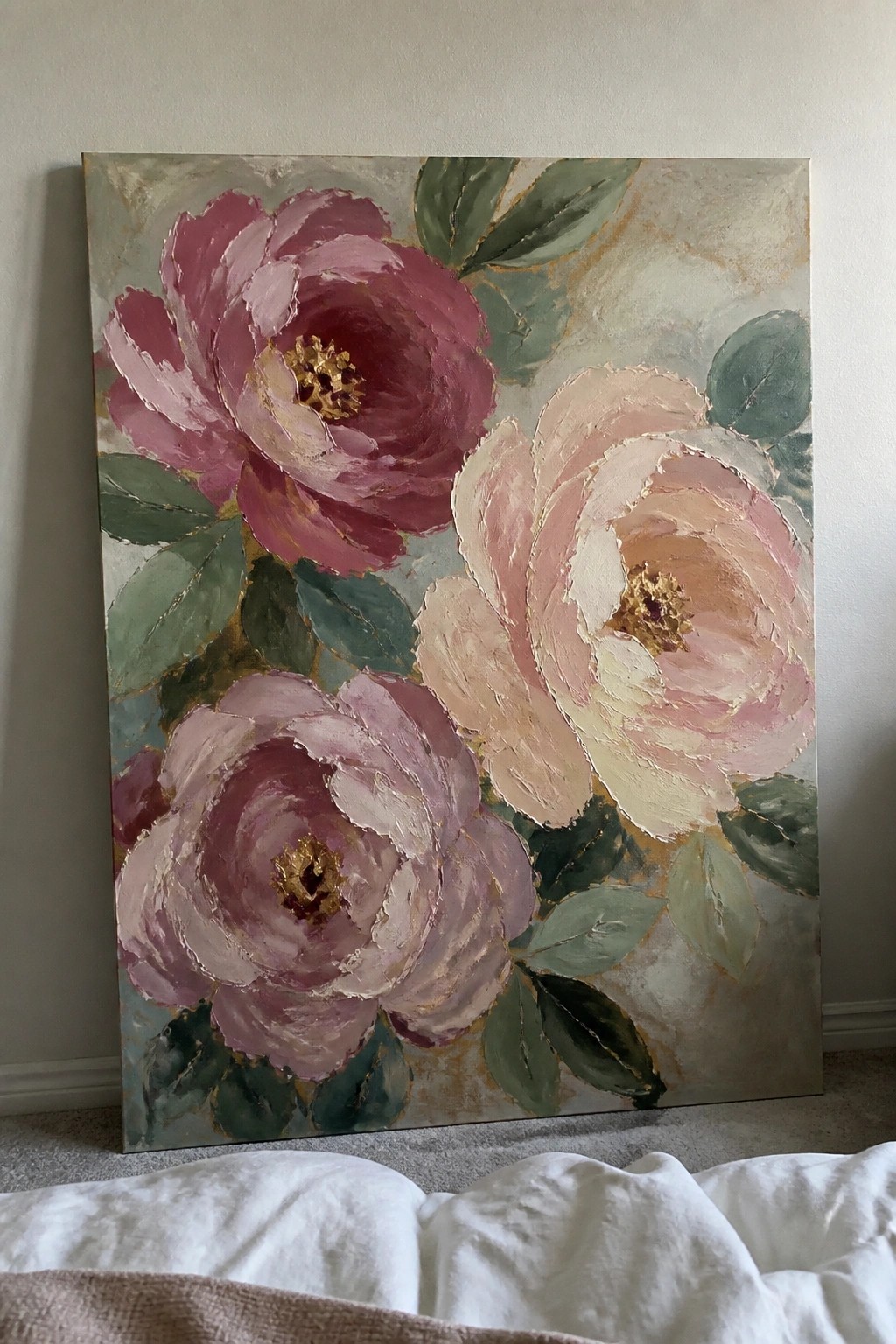 Textured painting of pink peonies with gold accents and green leaves on canvas against wall