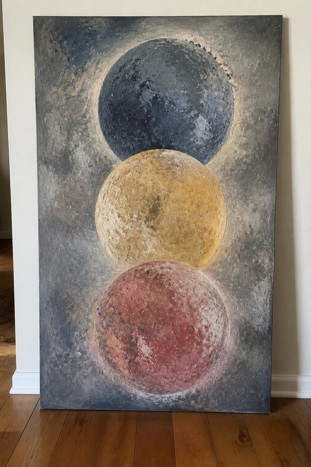 Large abstract painting with three textured spheres in blue, gold, and red.