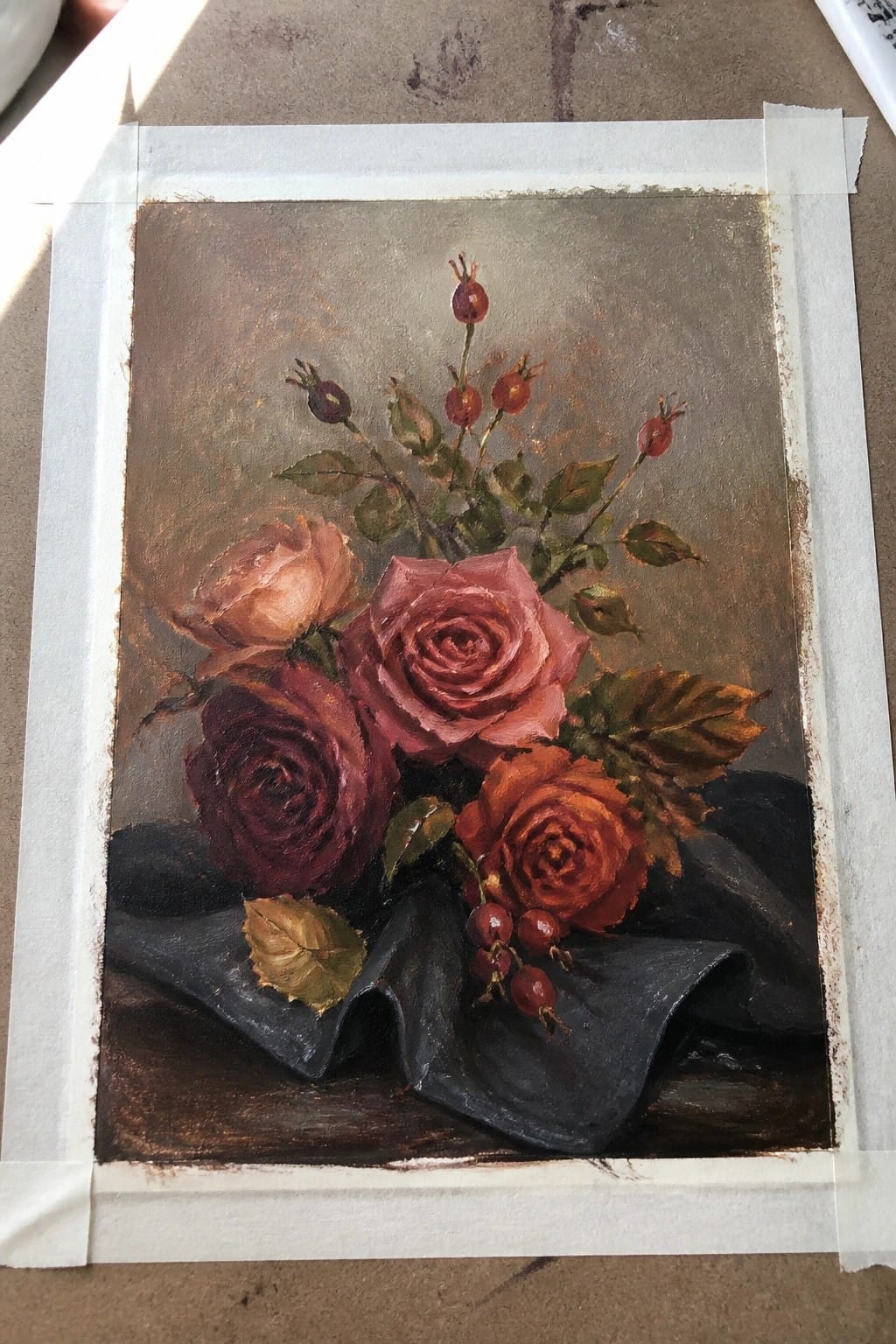 Oil painting of pink and red roses with rose hips on dark fabric.