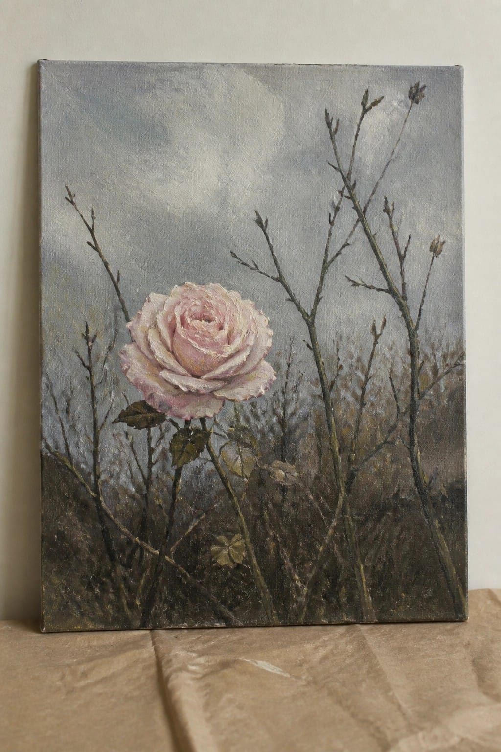 Oil painting of pale pink rose blooming amid thorny branches under a gray misty sky