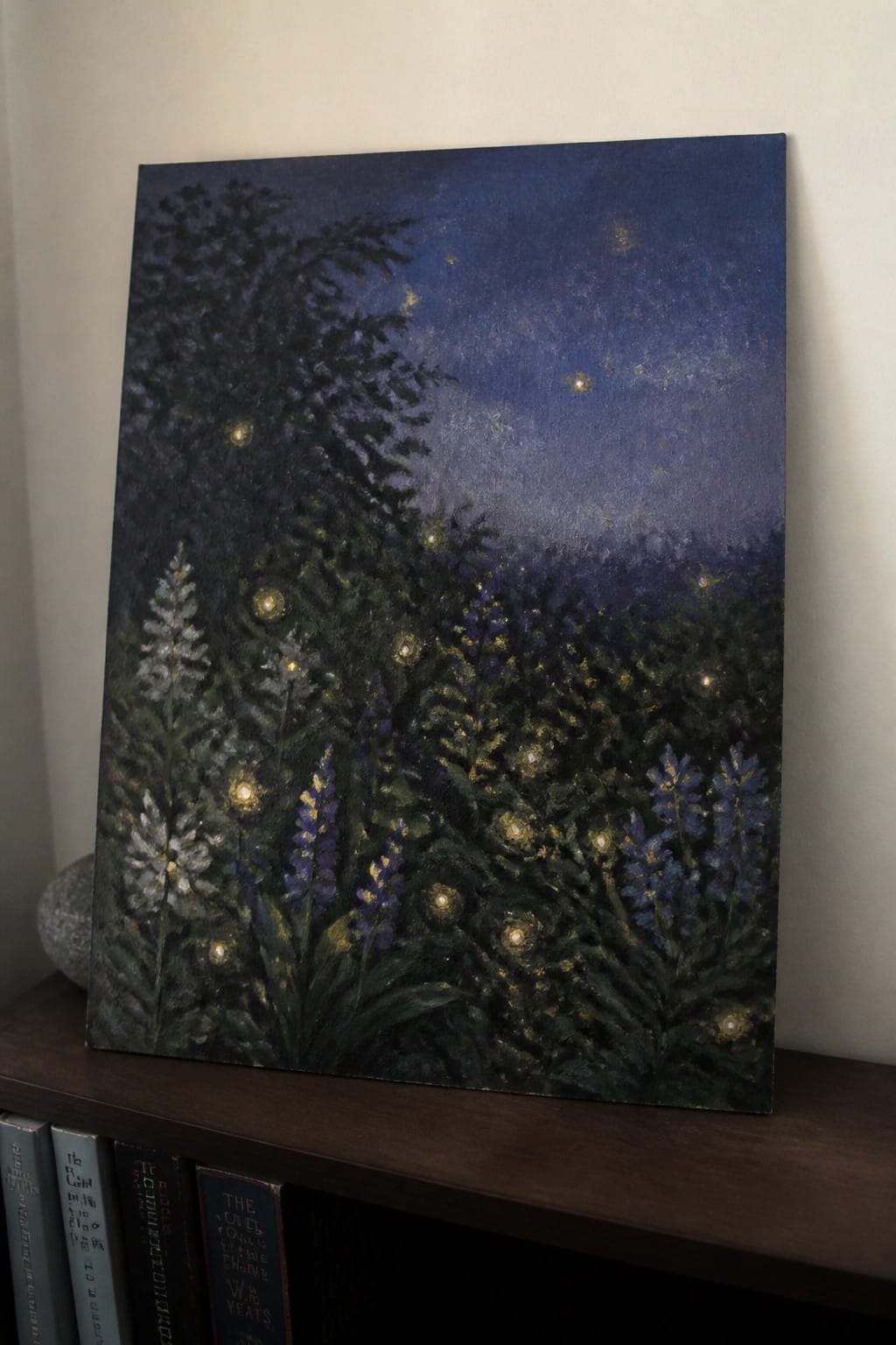 Starry night painting with glowing lights among purple flowers and trees on wooden shelf.