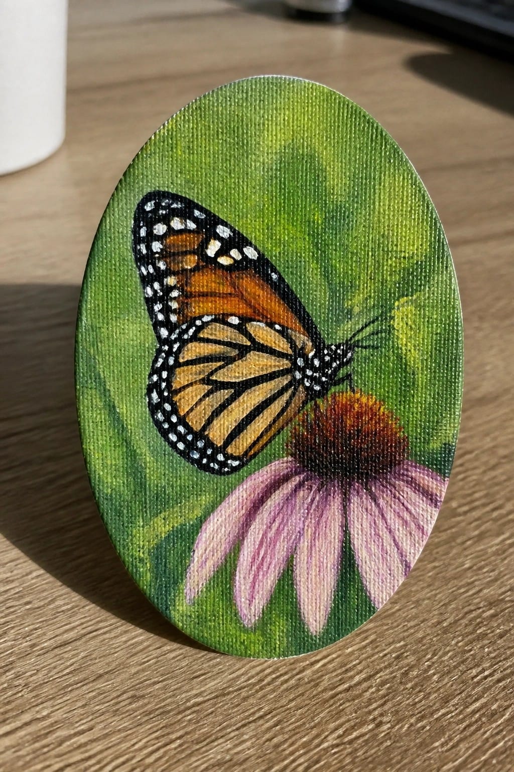 Monarch butterfly with orange black wings on pink coneflower against green oval canvas background