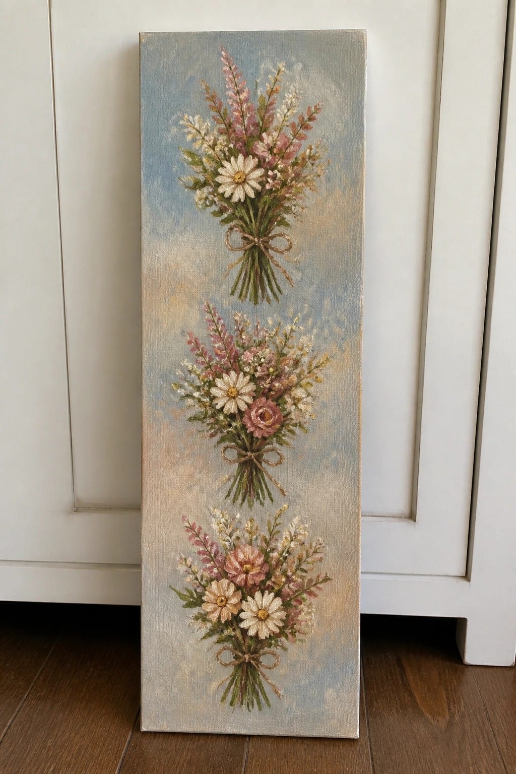 Tall canvas with three stacked floral bouquets tied with bows on soft blue background