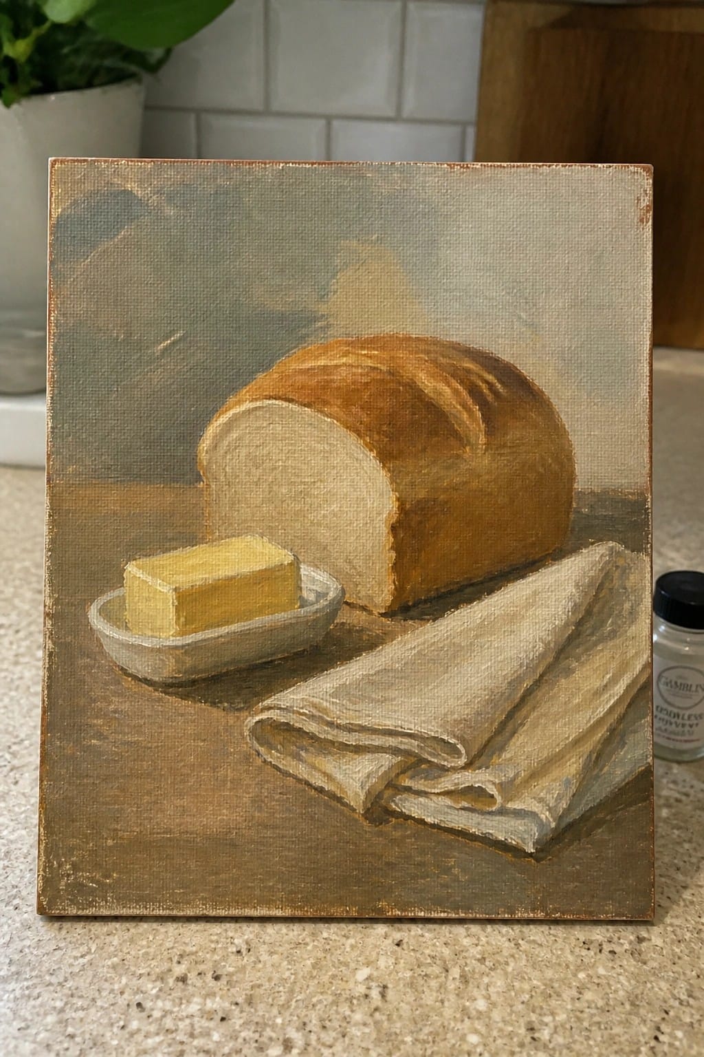 Oil painting of crusty bread loaf with butter dish and folded linen cloth.