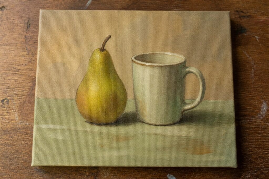Green pear beside white mug in muted still life painting on wood.