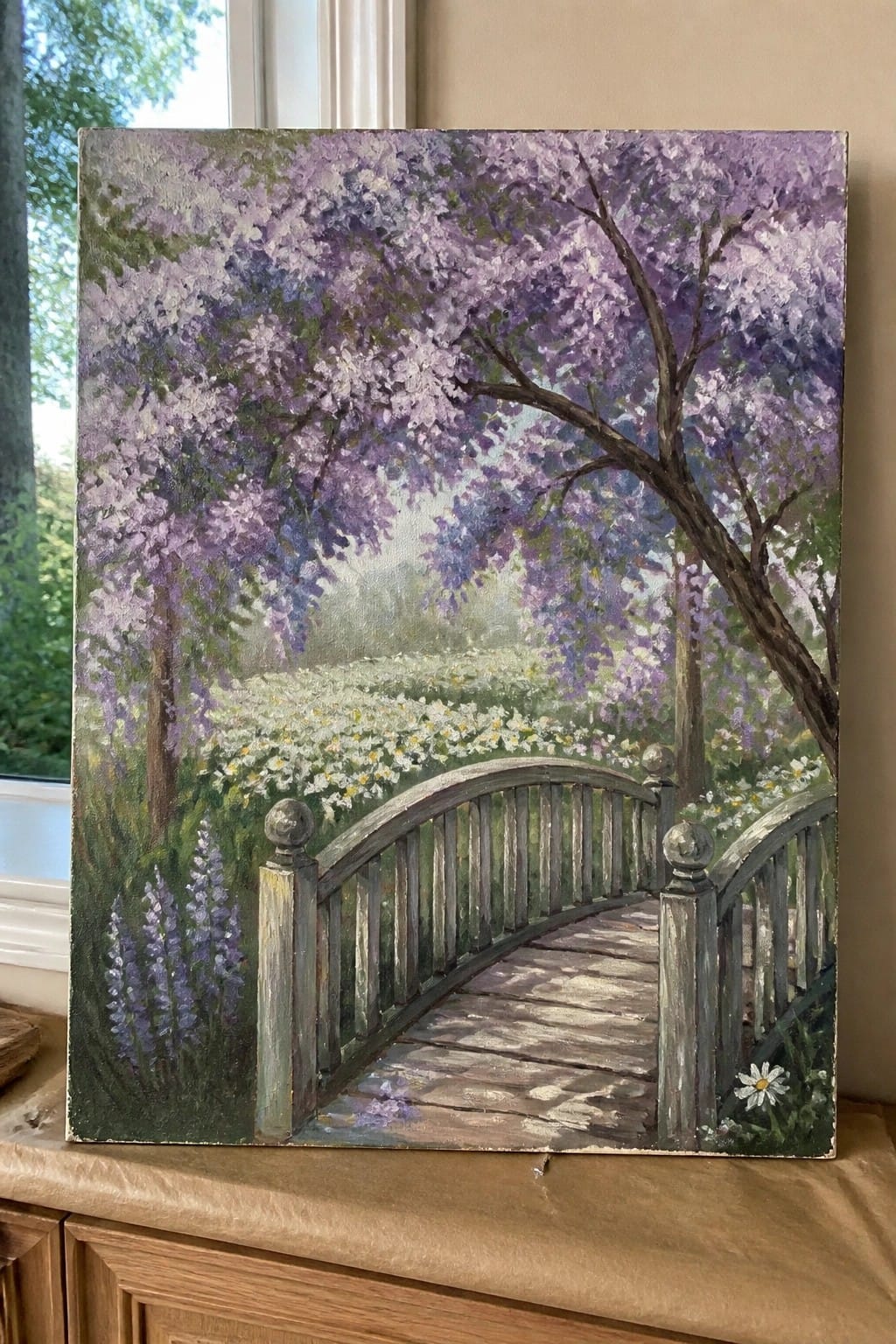 Realistic oil painting of arched wooden bridge under purple wisteria trees amid daisies.