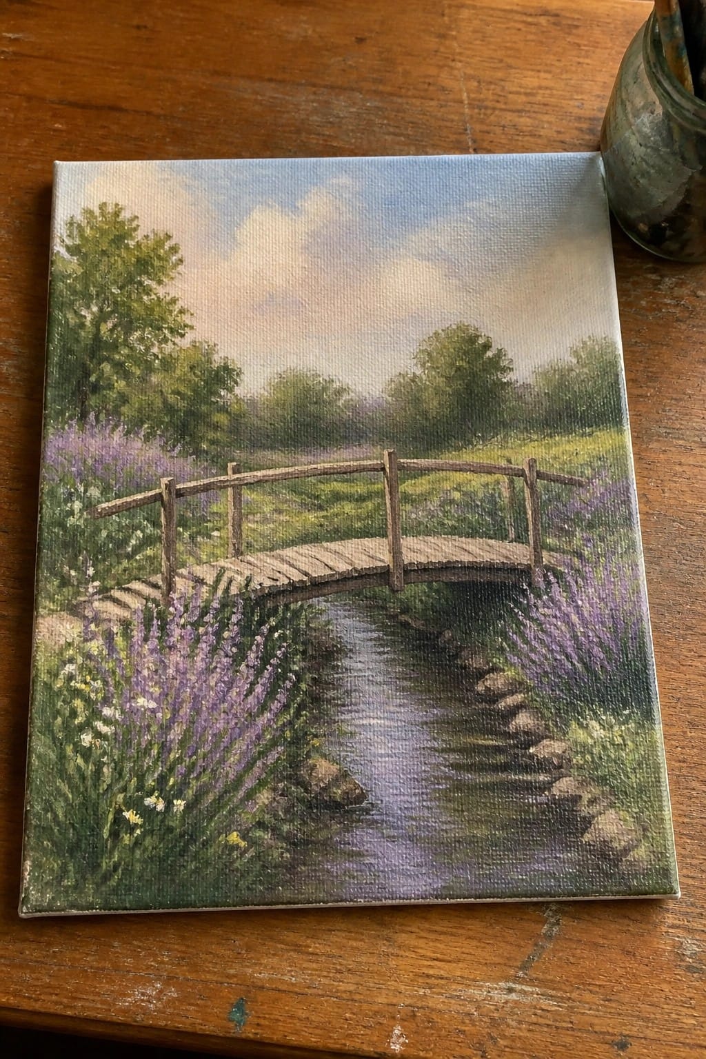 Realistic oil painting of wooden bridge over stream amid purple wildflowers and green trees.
