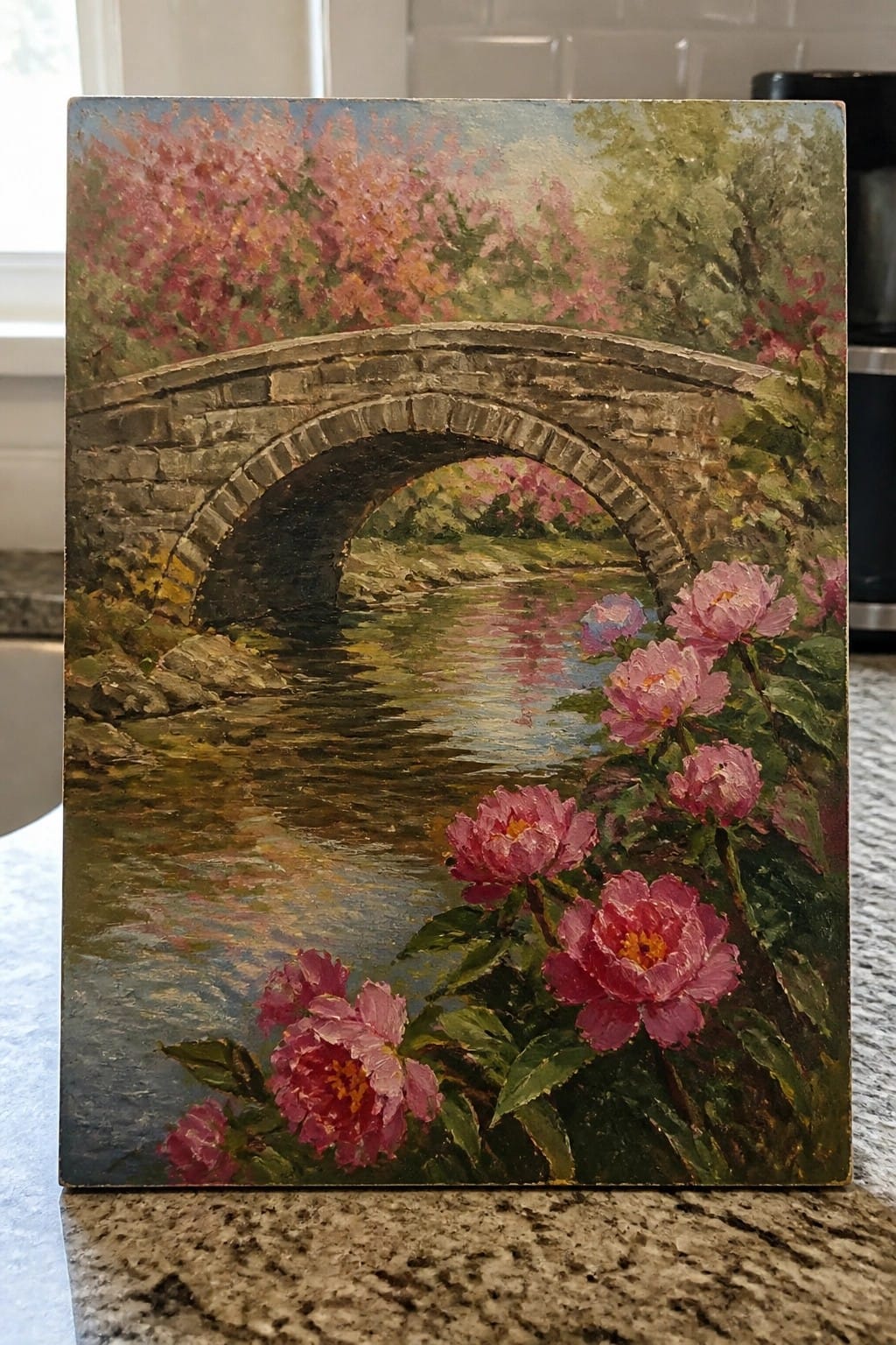 Stone bridge arches over river amid pink peonies and blooming cherry trees in oil painting.