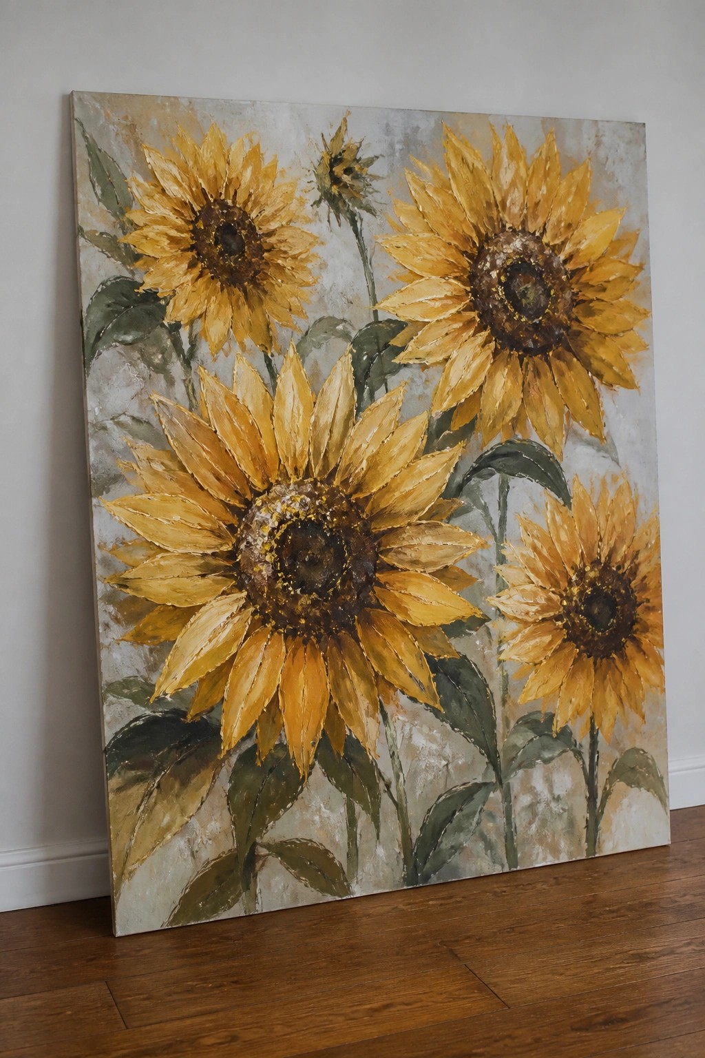 Large textured painting of yellow sunflowers leaning against wall on wooden floor