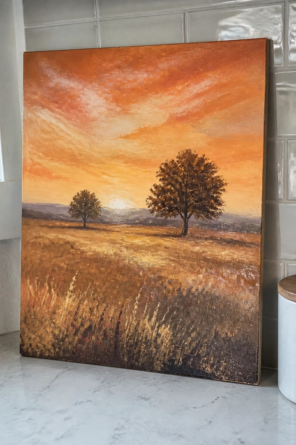 Oil painting of a sunset landscape with two trees in a golden field under an orange sky.