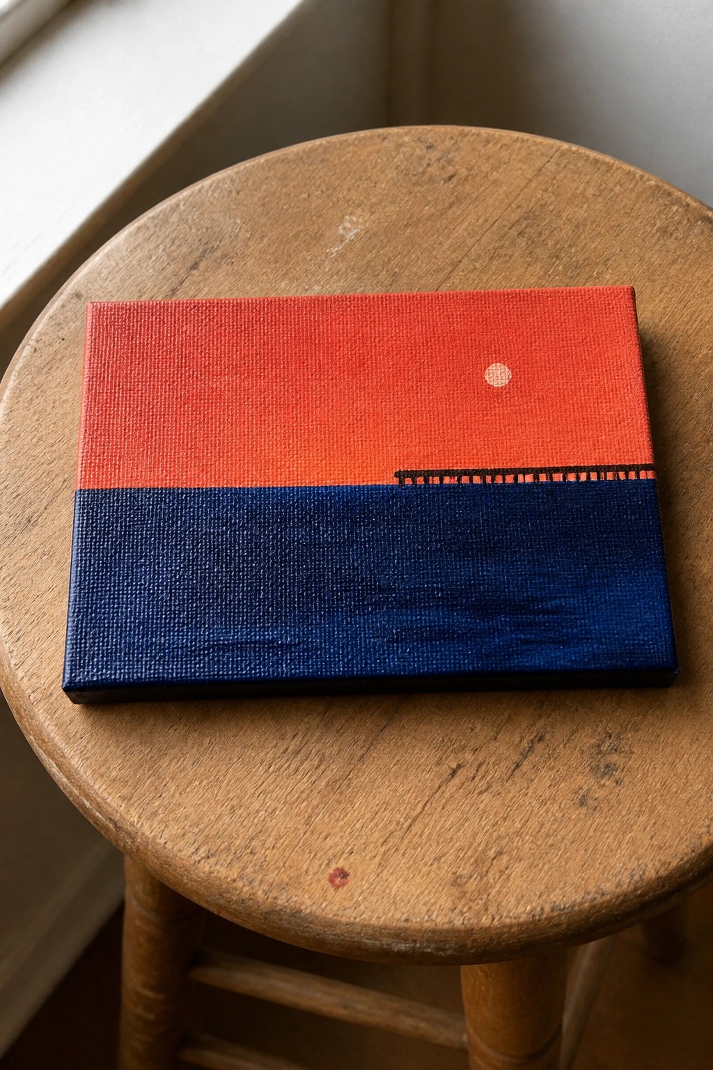 Red and blue painting with white dot and black line on wooden stool.