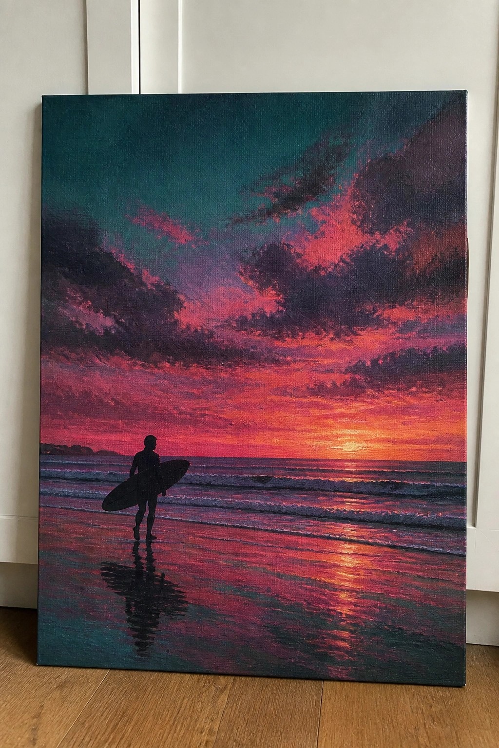 Silhouetted surfer carries board across wet sand under vibrant pink-orange sunset sky