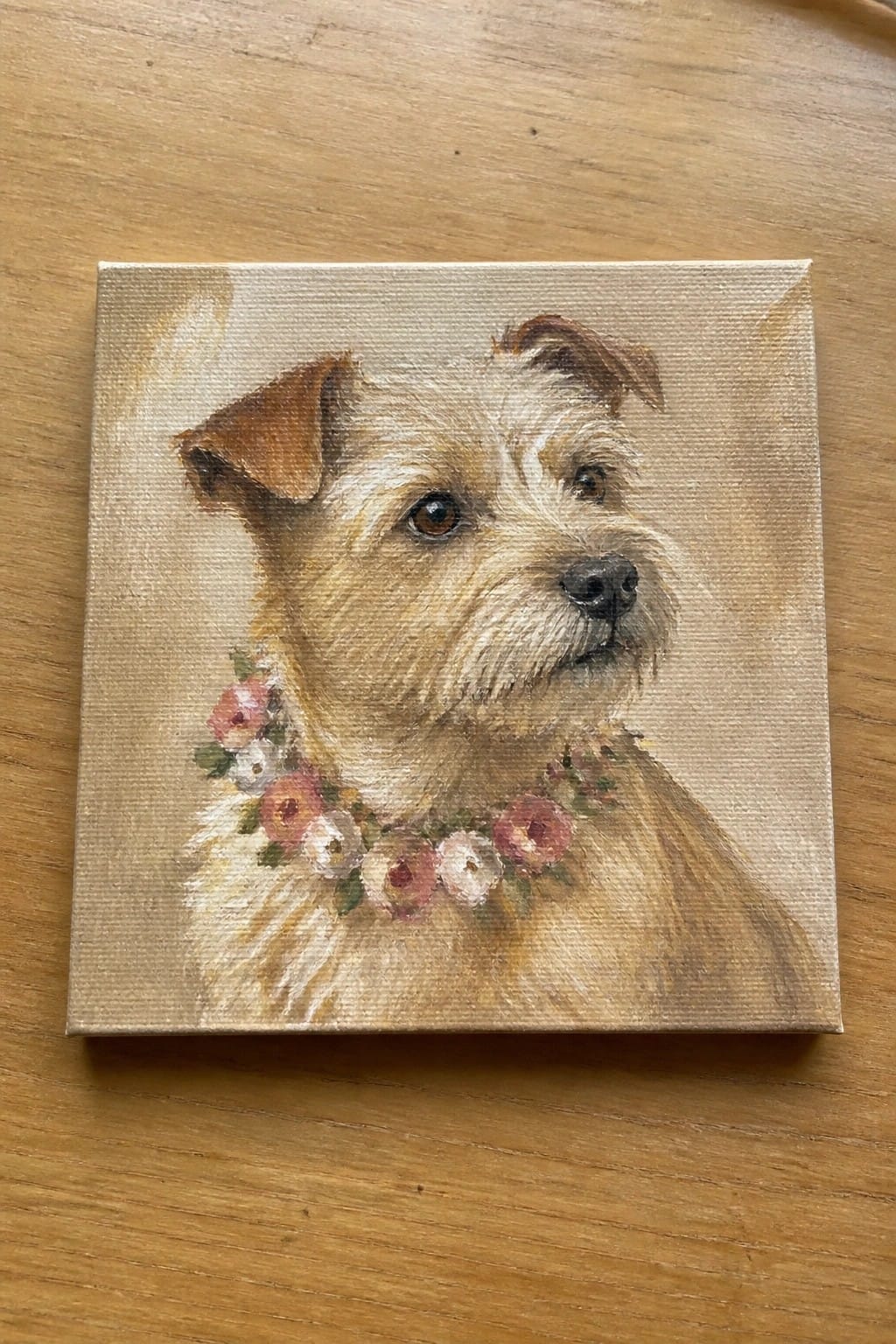 Square canvas painting of terrier dog with pink floral collar on wooden table