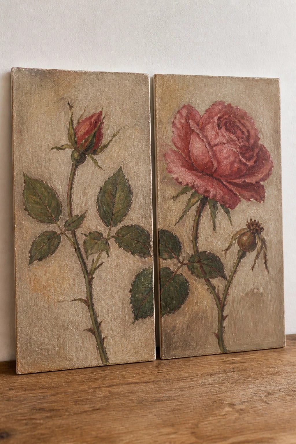 Two side-by-side rose paintings on wood, one bud and one full bloom.