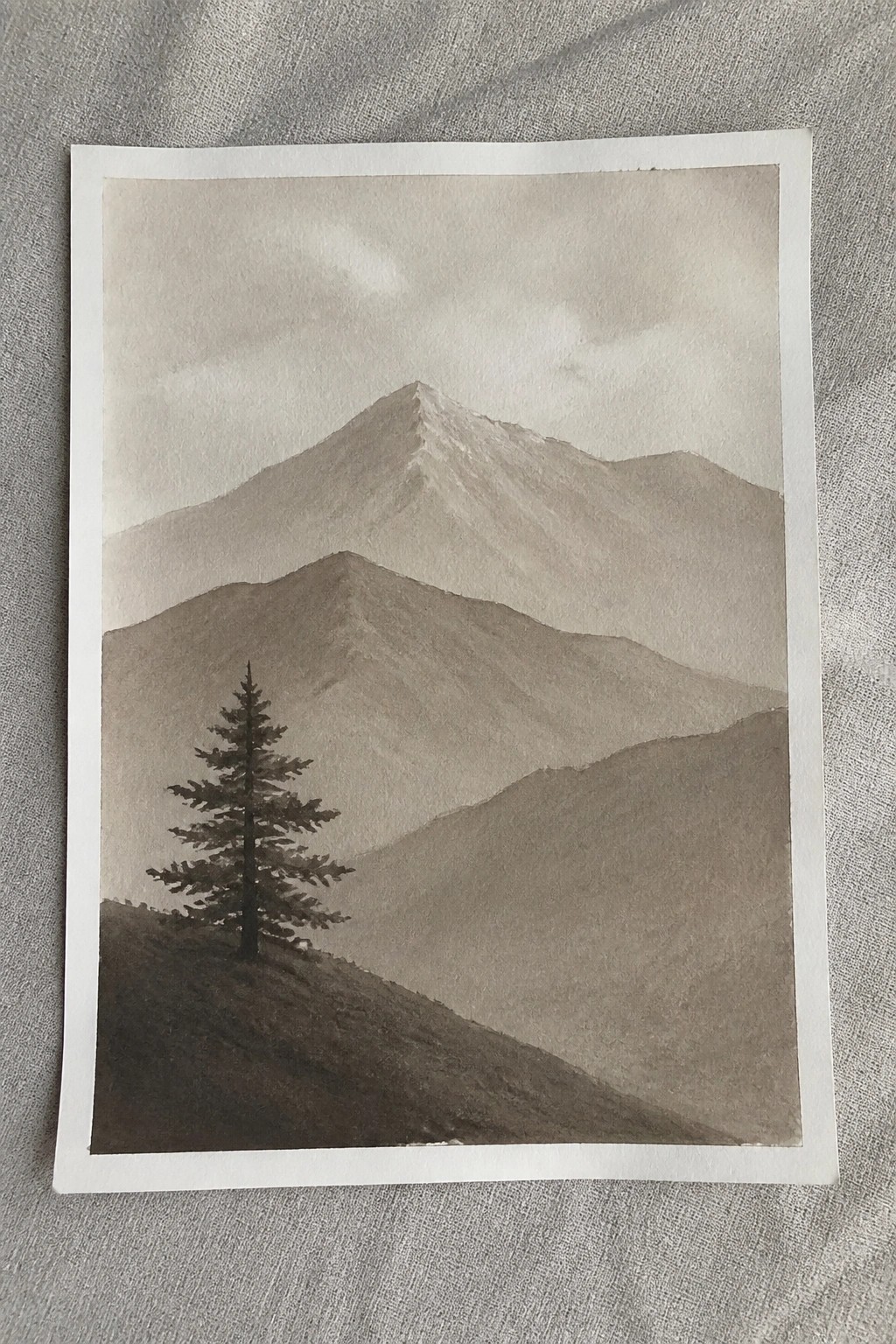 Watercolor landscape of a lone pine tree on a misty mountain slope.