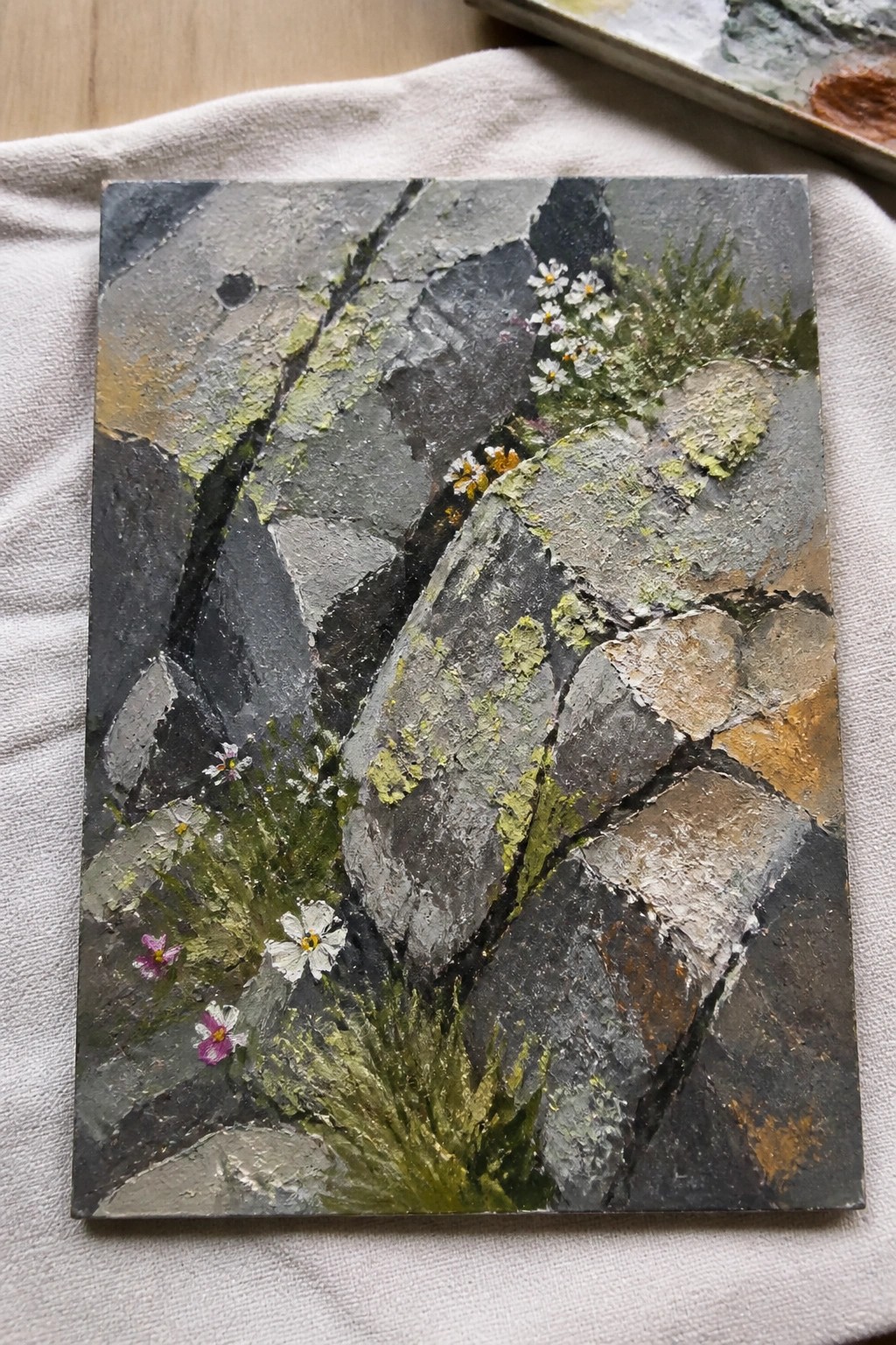 Textured painting of cracked gray rocks with white daisies, purple flowers, and lichen.