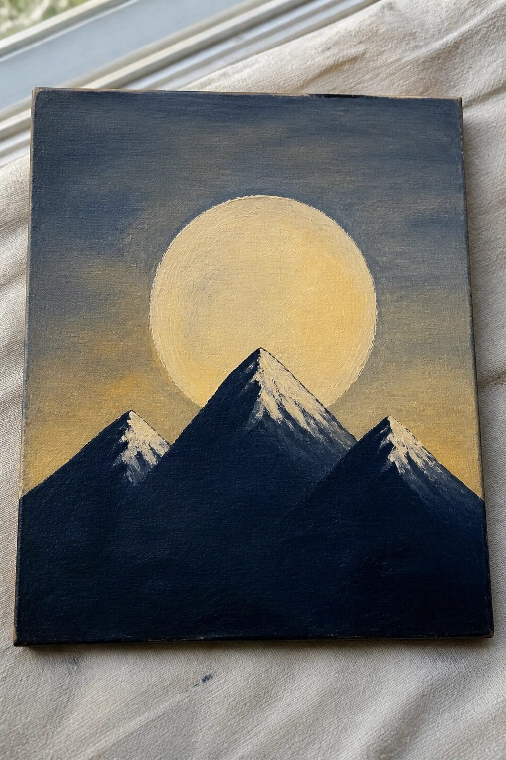 Three snow-capped mountains beneath a large yellow moon in a gradient sky.