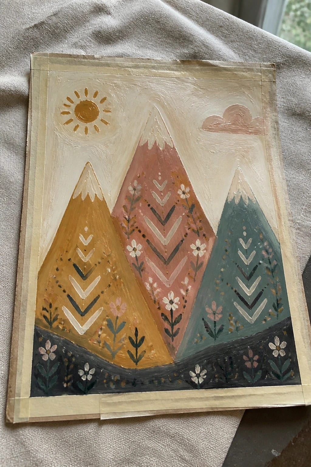 An oil painting of three mountains in yellow, pink, and teal with chevron patterns and flowers, plus a sun and cloud.