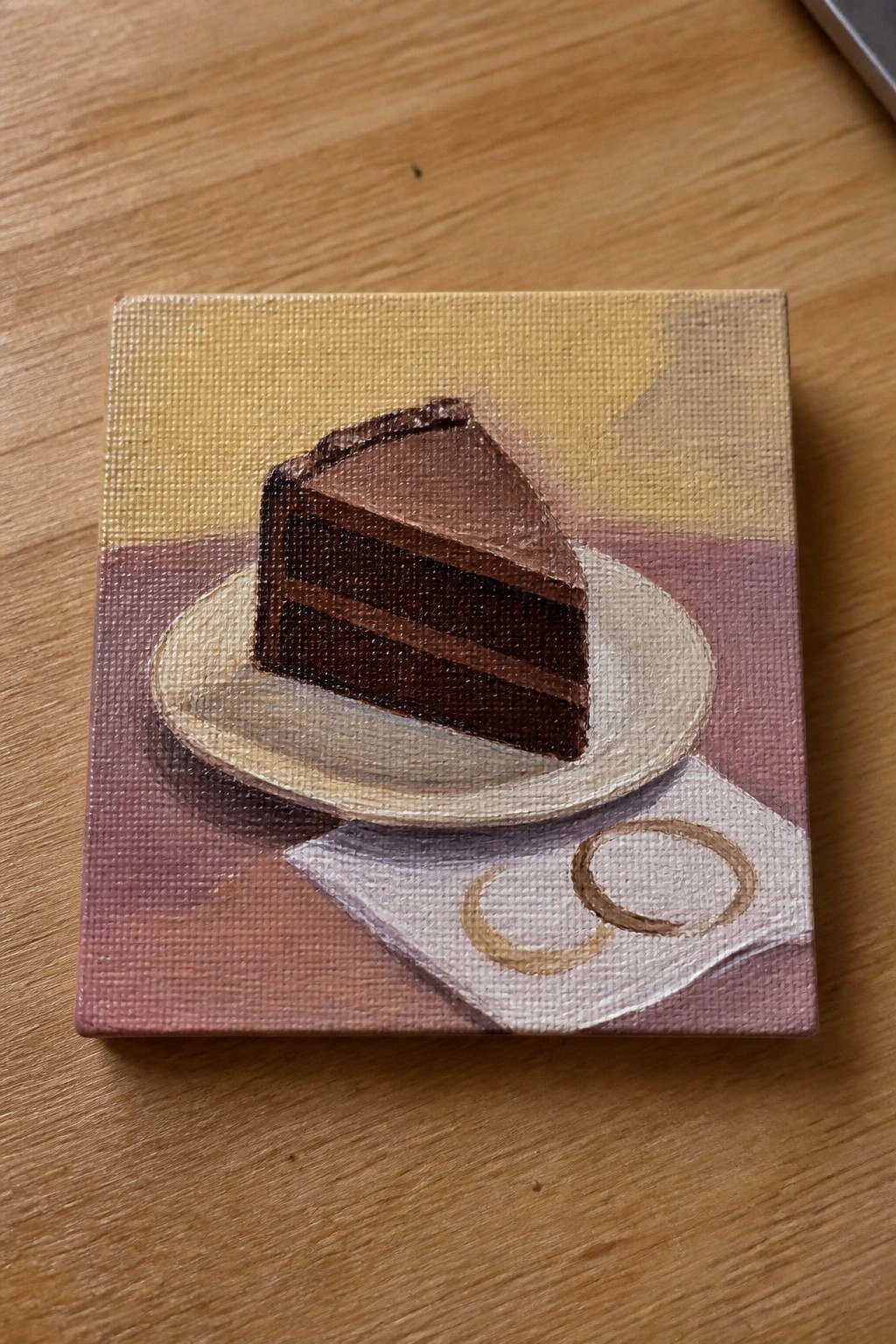 Small painting of chocolate cake slice on plate over coffee-stained napkin