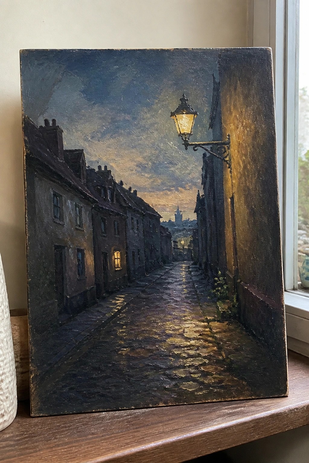 A realistic oil painting of a narrow cobblestone street at twilight lined with old buildings and lit by one glowing street lamp.