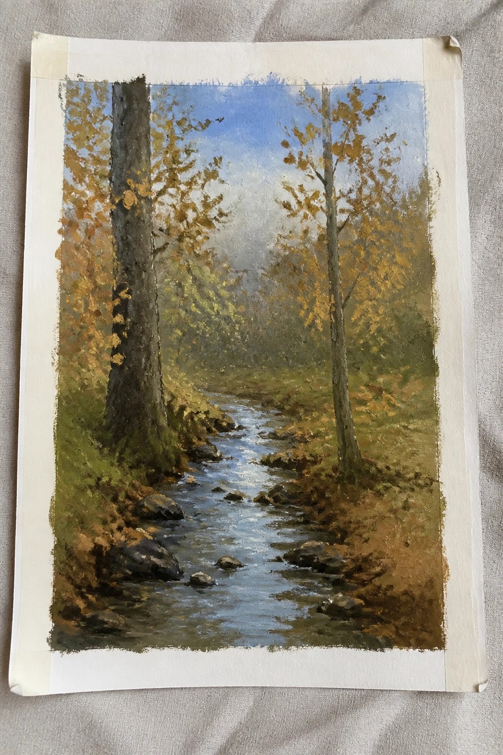 Oil painting of creek winding through autumn forest with golden trees and rocks.