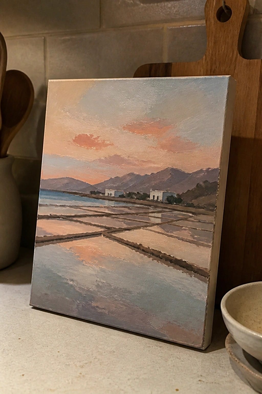 Canvas painting of sunset over mountains, water, and geometric fields on kitchen counter