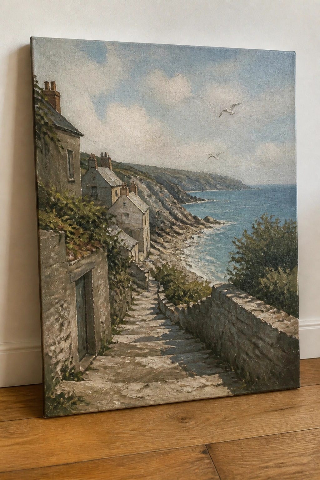 Stone steps descend past ivy-covered cottages to a rocky blue coastline with seagulls.