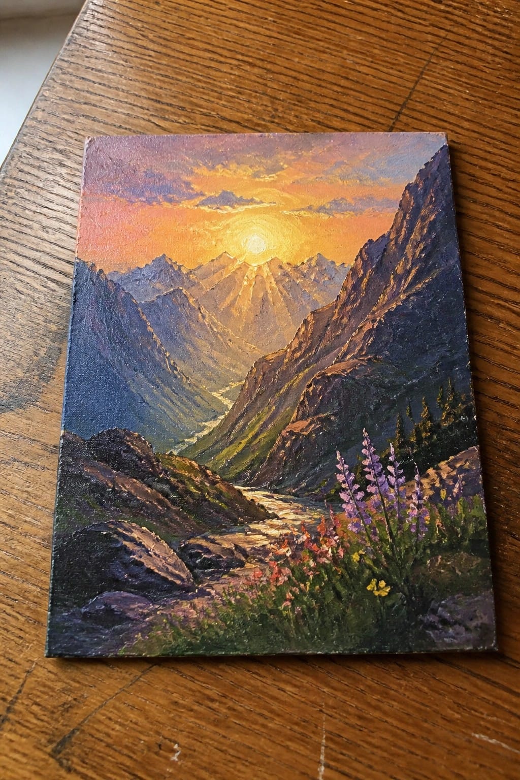 Vivid painting of sunset over rugged mountains with river and blooming wildflowers