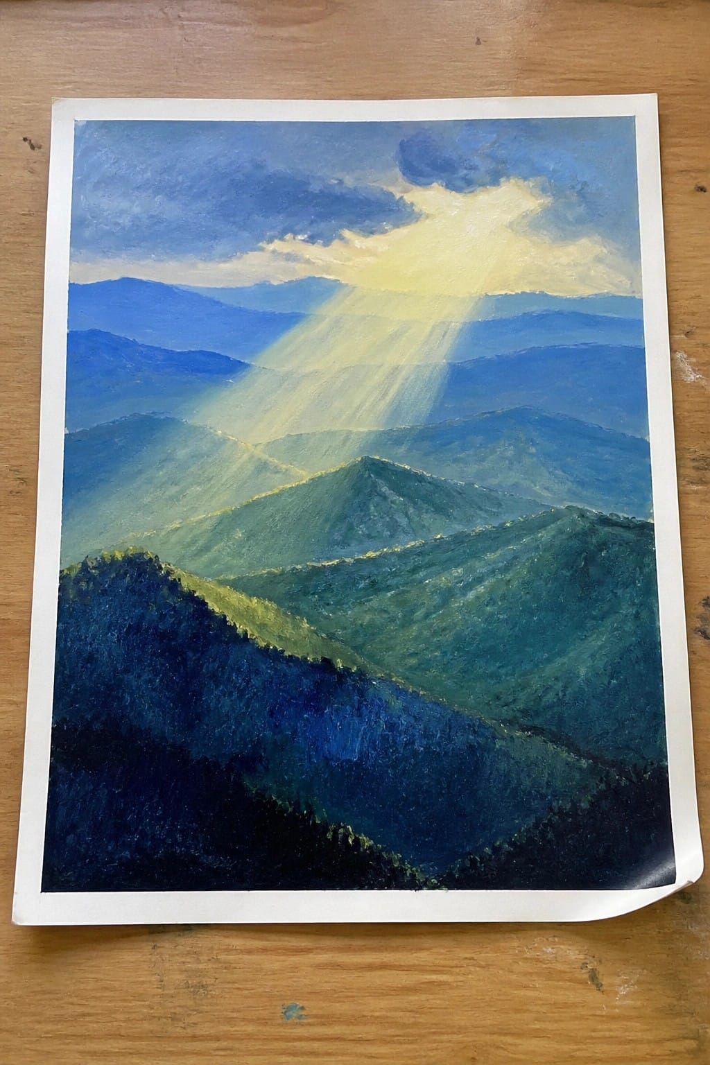 Impressionistic painting of sun rays beaming over layered blue-green mountain ranges under clouds