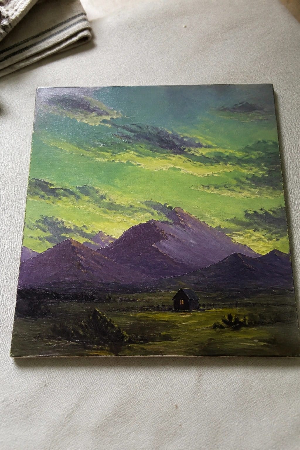 Vibrant oil painting of purple mountains under swirling green sky with lone cabin