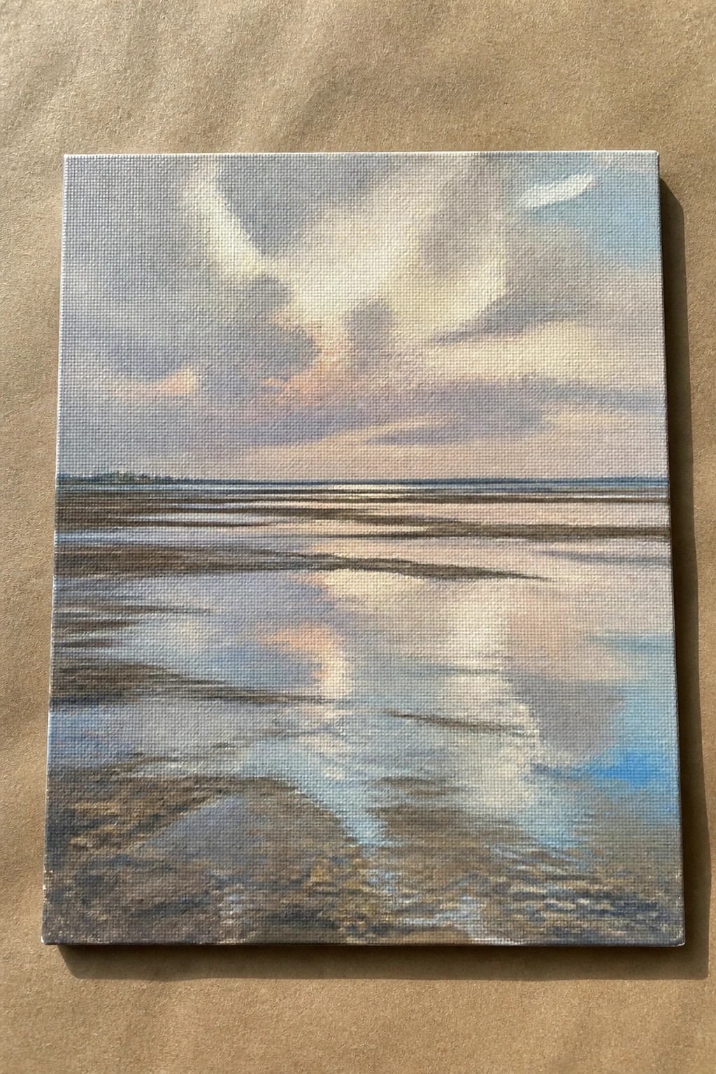 Canvas painting of cloudy sky reflected on wet tidal flats at sunset.
