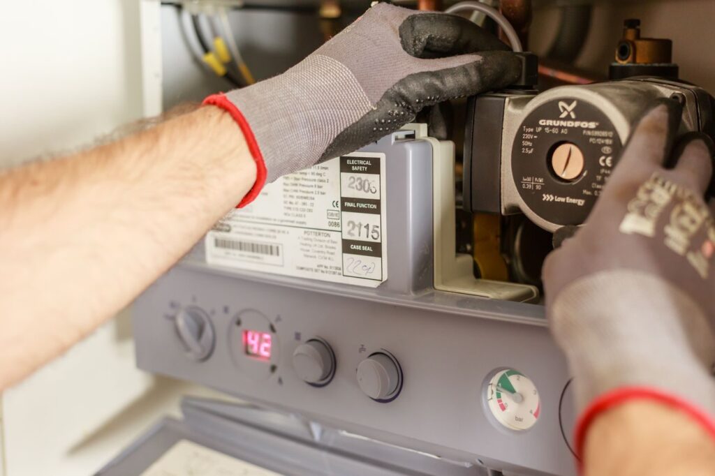 Technician gloves servicing indoor boiler circulation pump and controls